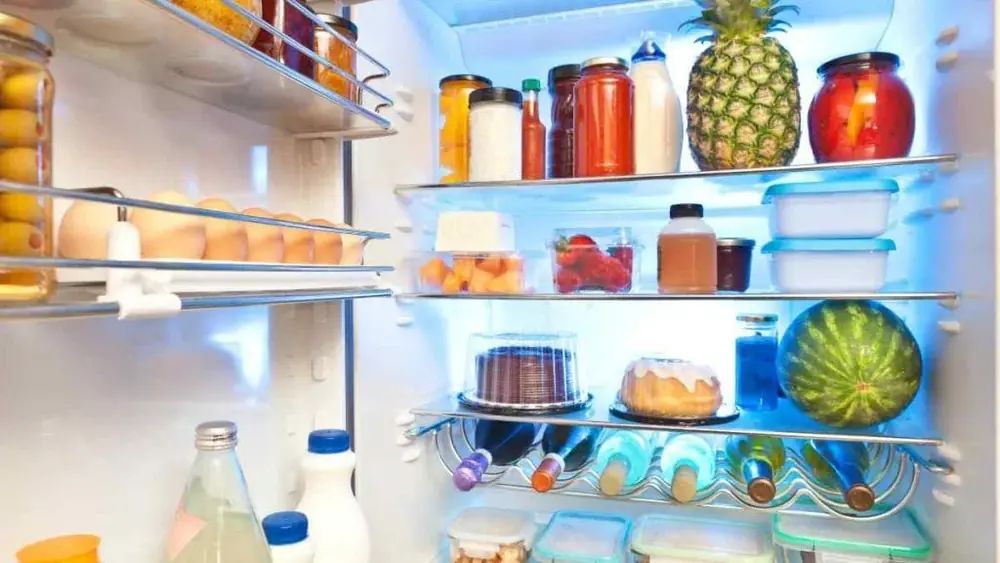 Geladeira aberta, com as prateleiras cheias de alimentos