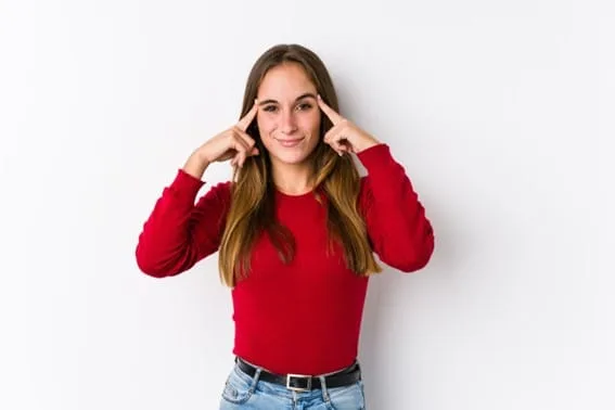 Mulher de blusa vermelha com os dedos apontando para as têmporas