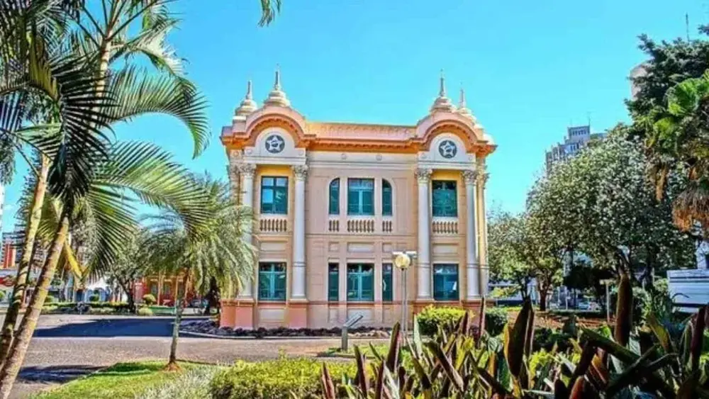 Praça arborizada com um casarão histórico ao fundo