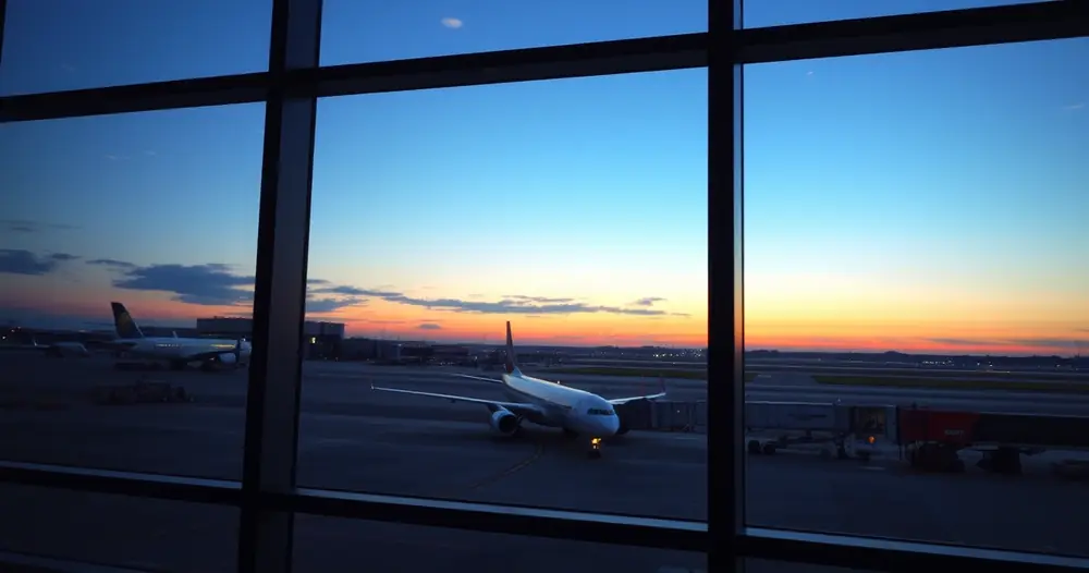 Janela de terminal de aeroporto com um avião do lado de fora, ao amanhecer