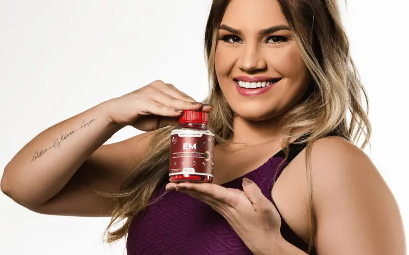 Mulher sorrindo segurando um pote de suplemento